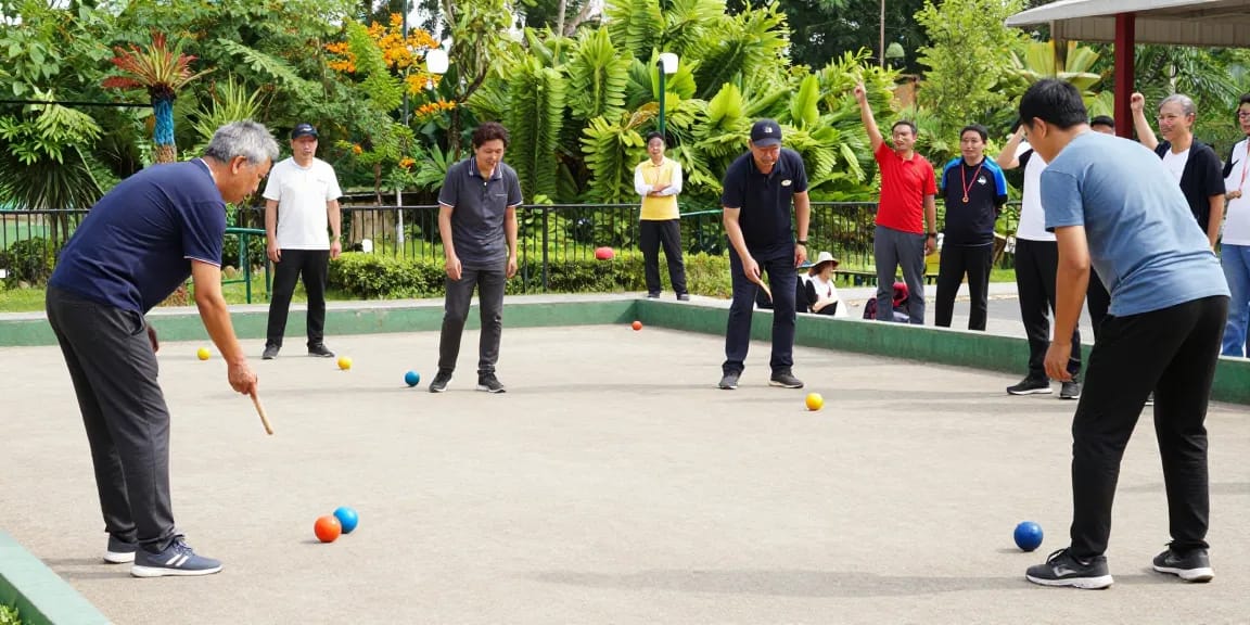 Pemain petanque di fopikotabanjarma.org berkompetisi di lapangan terbuka yang cerah.